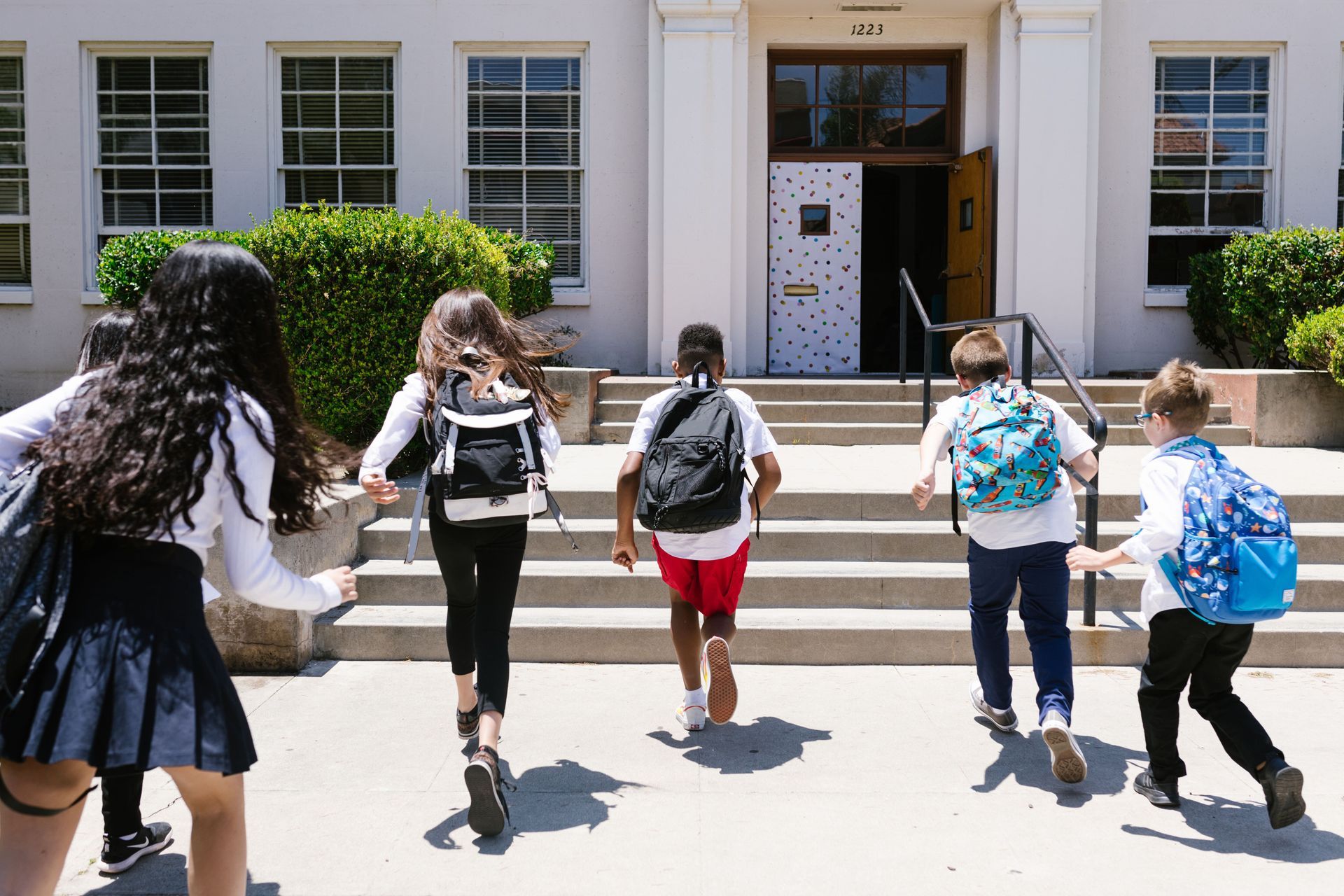 Students walking up steps into a school building with backpacks