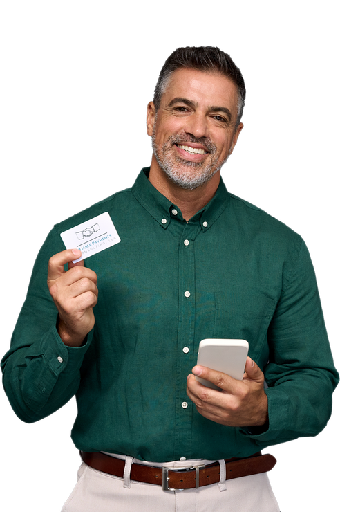 A man in a green shirt is holding a credit card and a cell phone.