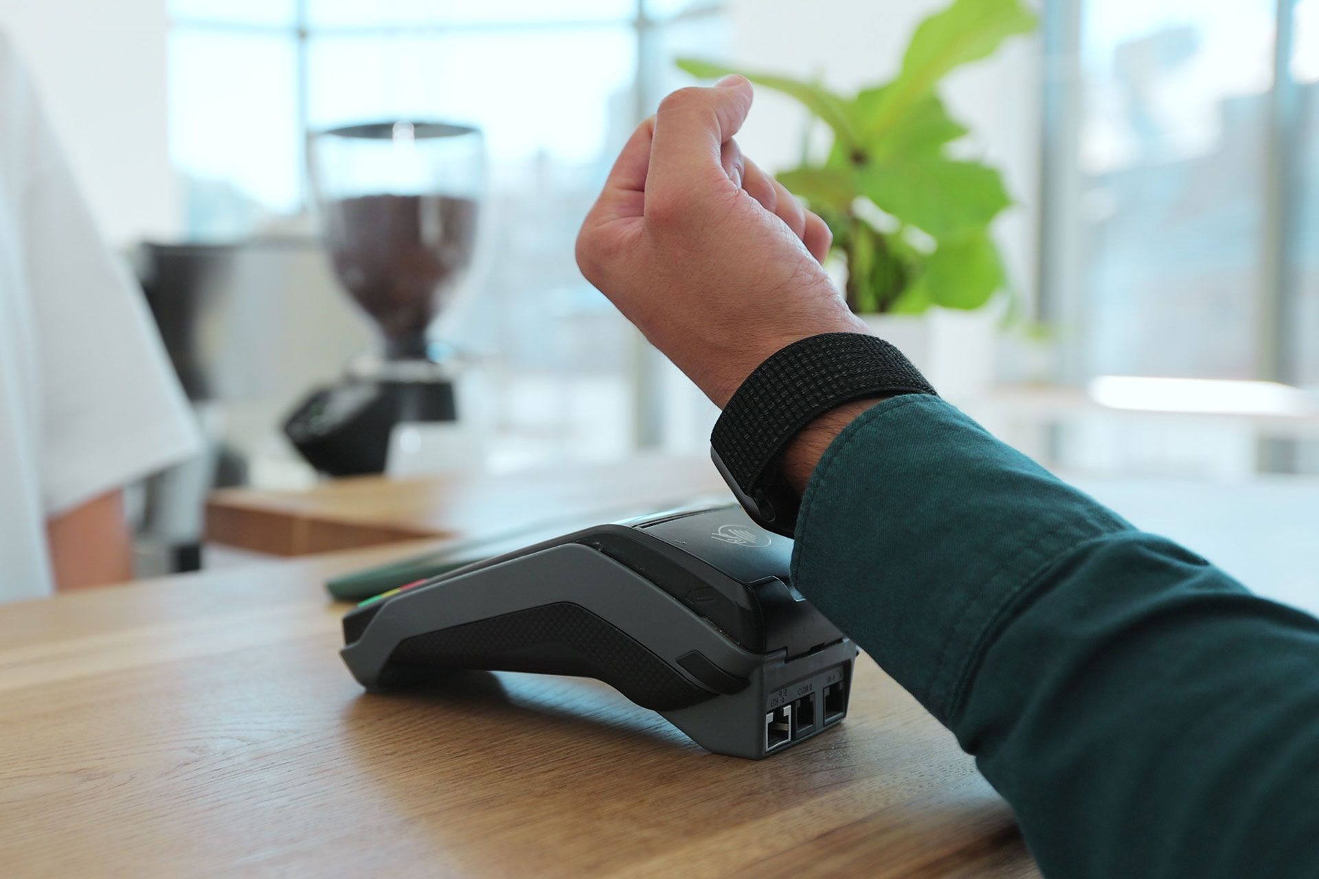 A man wearing a smart watch is using a credit card machine.