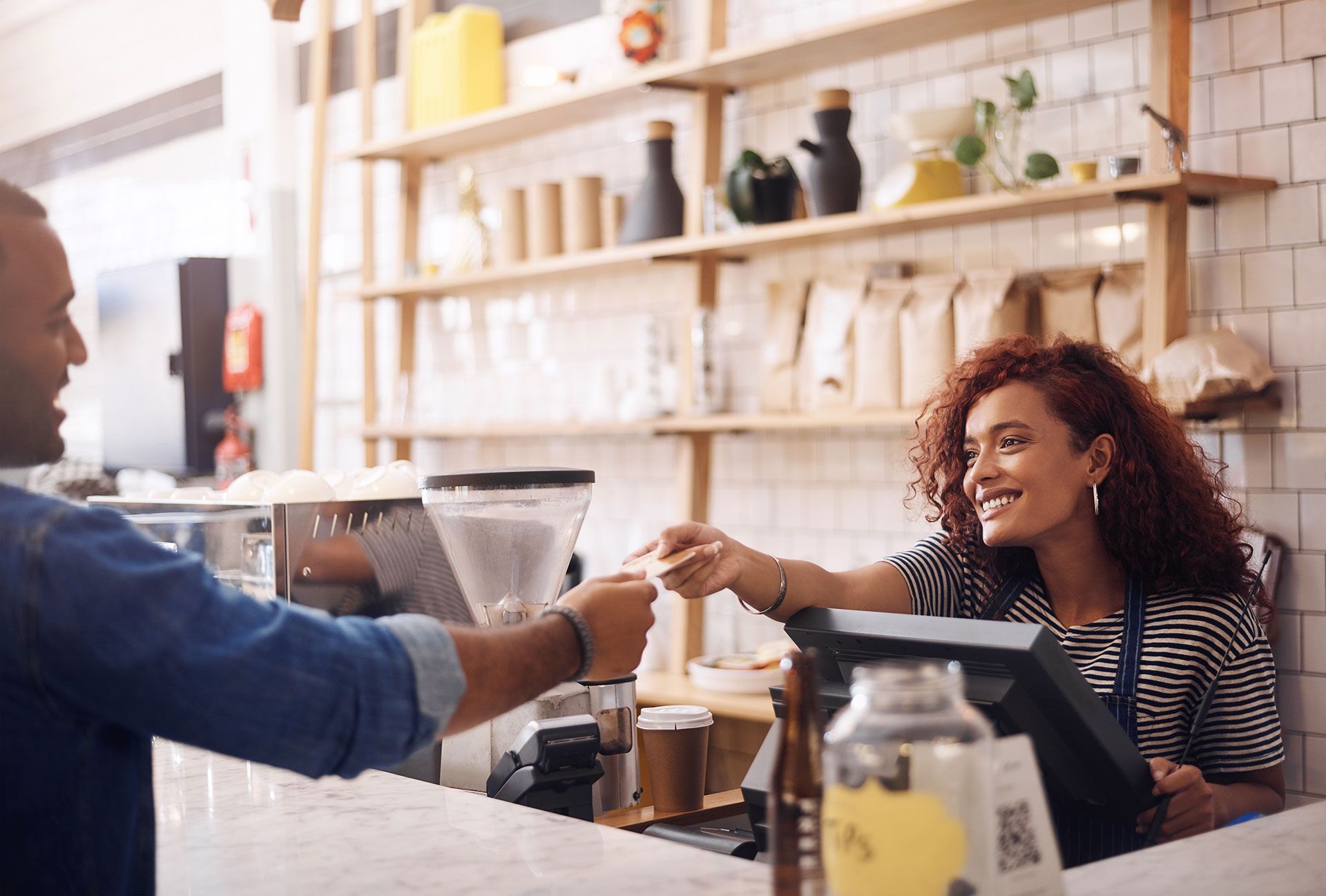 A man is giving a credit card to a woman in a coffee shop.
