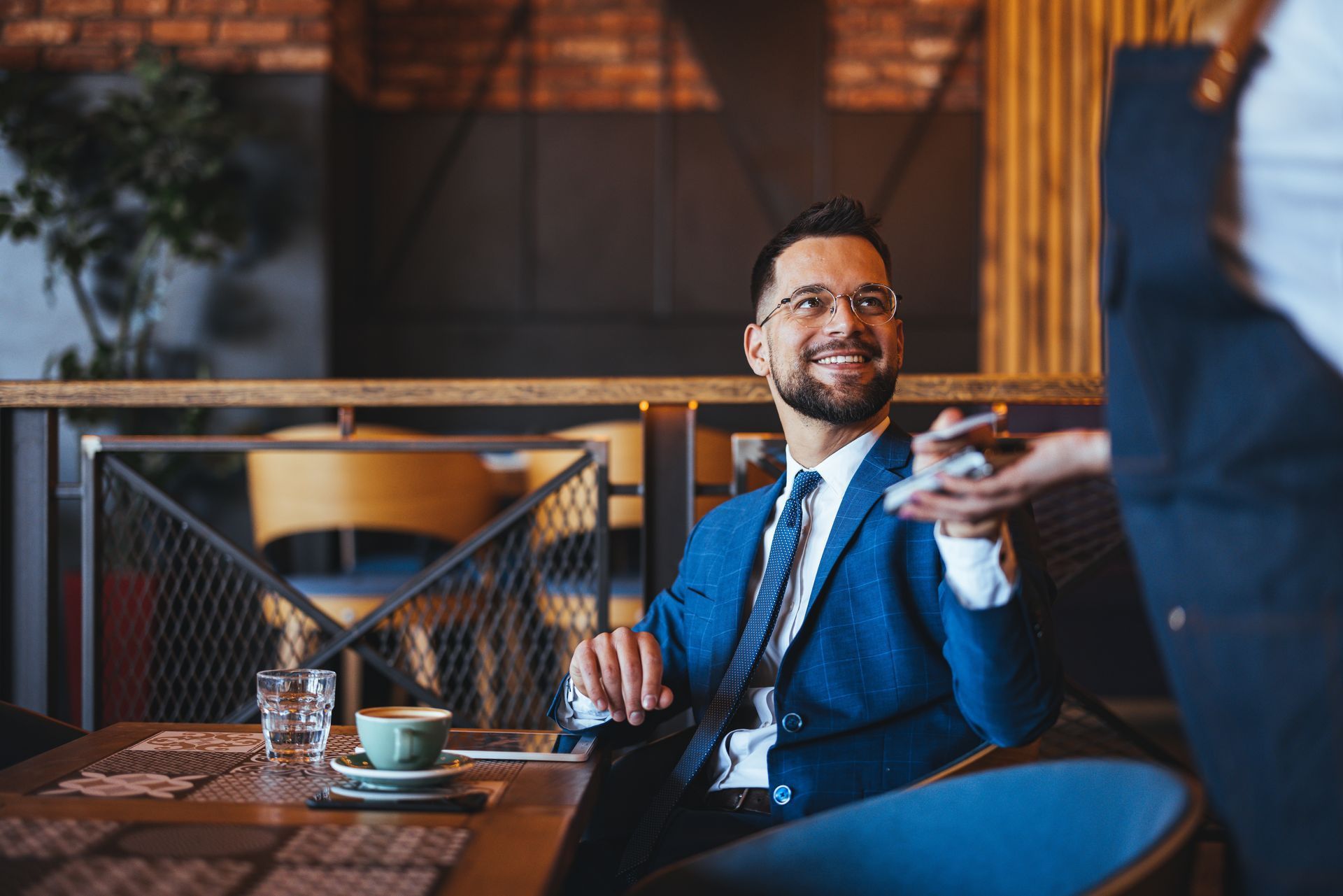 A man in a suit and tie is sitting at a table in a restaurant.