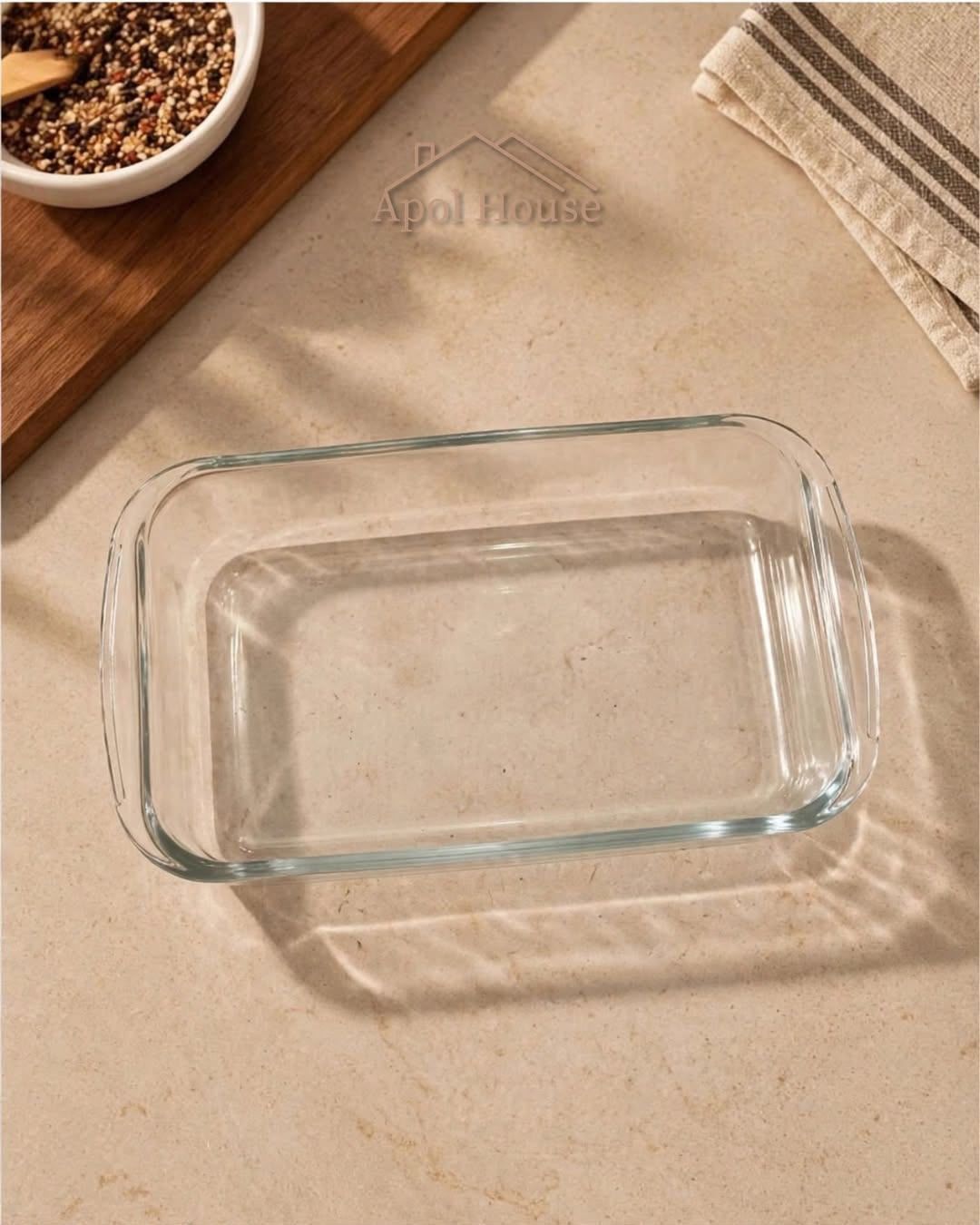 Fuente de vidrio rectangular vacía sobre un mantel beige, con una cuchara y un cuenco de frijoles cerca