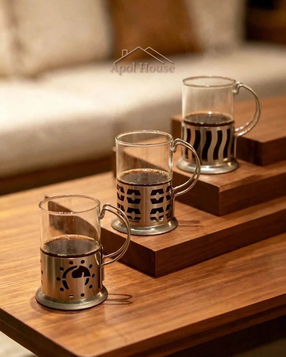 Tres vasos de vidrio con fundas metálicas en una escalera de madera de exposición.
