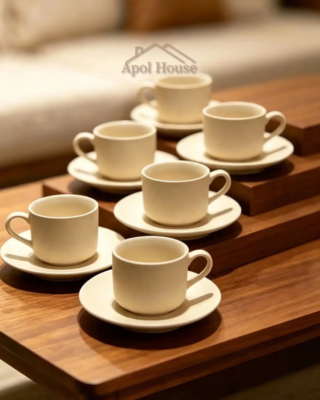 Cinco tazas blancas de café sobre platillos, dispuestas en una mesa de madera