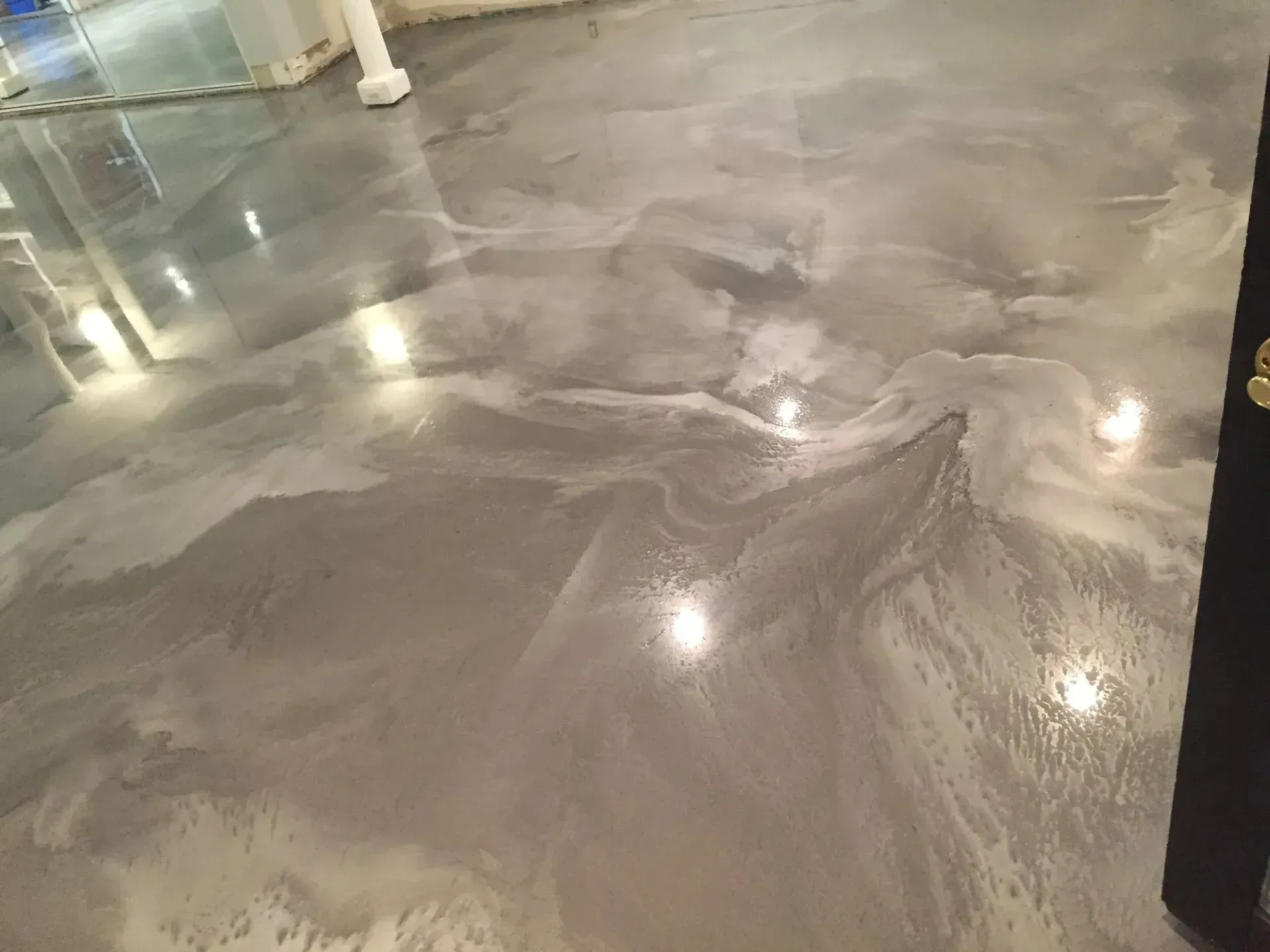 Glossy gray epoxy flooring with swirling patterns reflecting light.