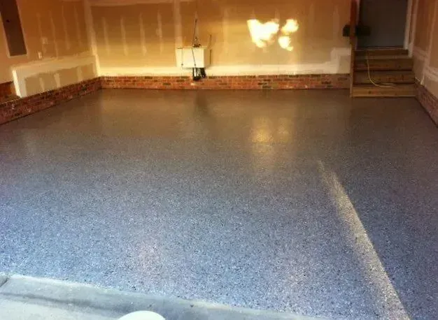 Garage with a gray speckled epoxy floor and exposed drywall walls.