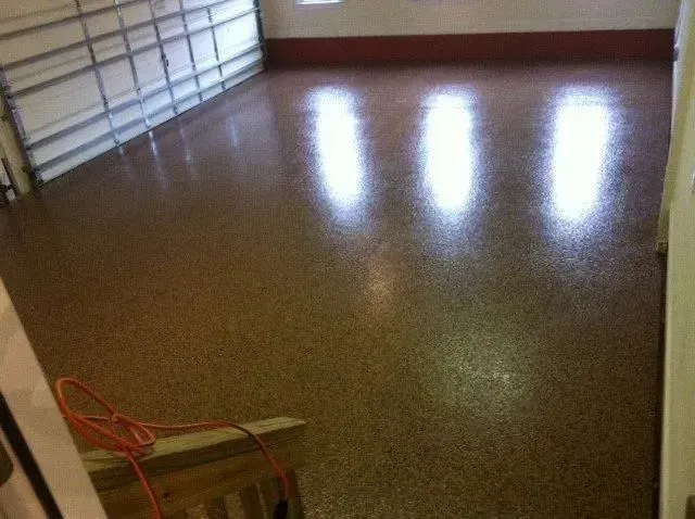 Garage floor with a speckled, glossy finish reflecting bright lights.