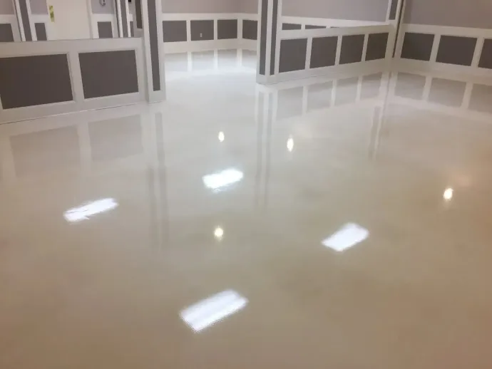 Shiny, light-colored floor reflecting overhead lights in a room with white paneled walls and dark trim.