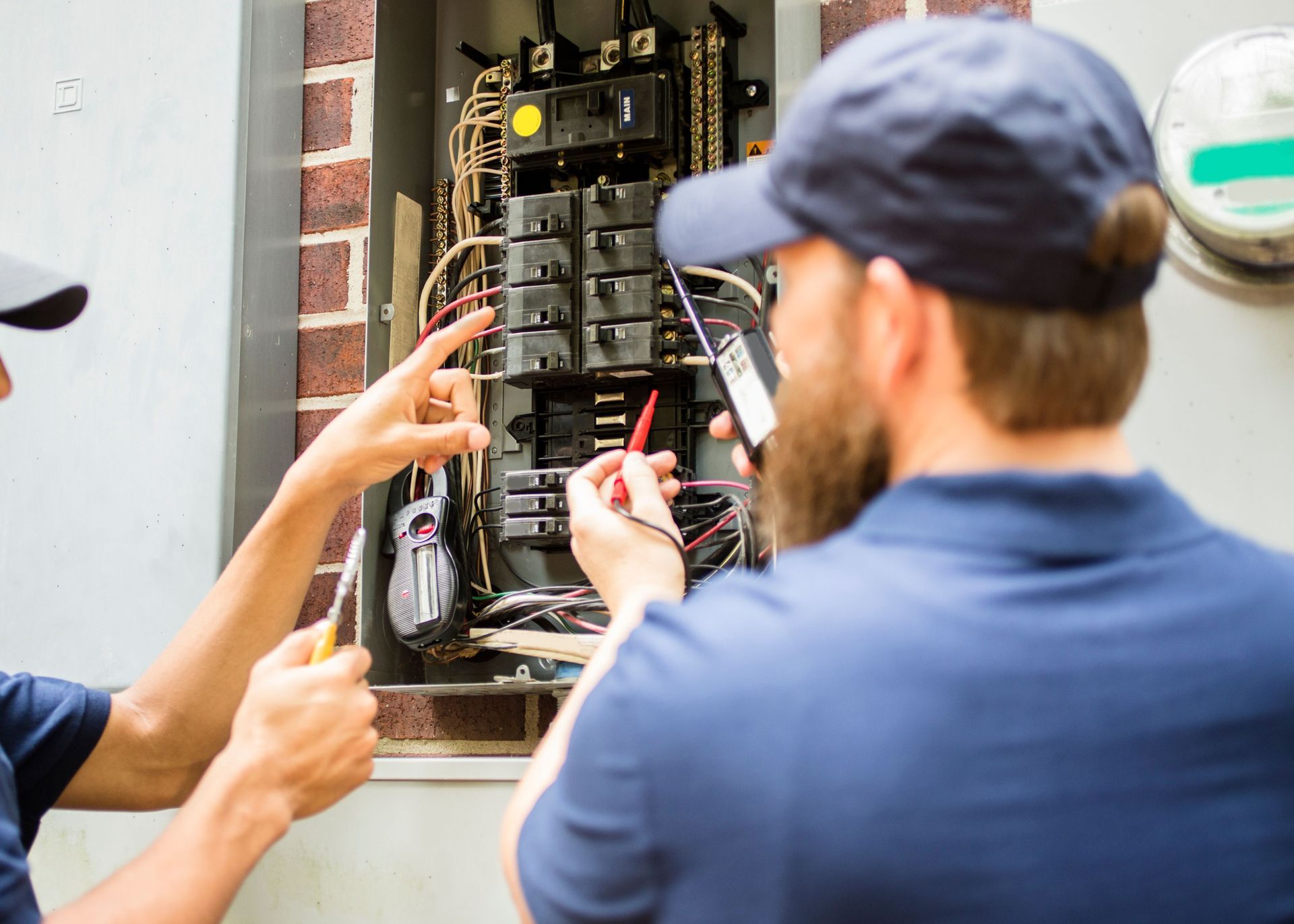 Two men are working on an electrical box.