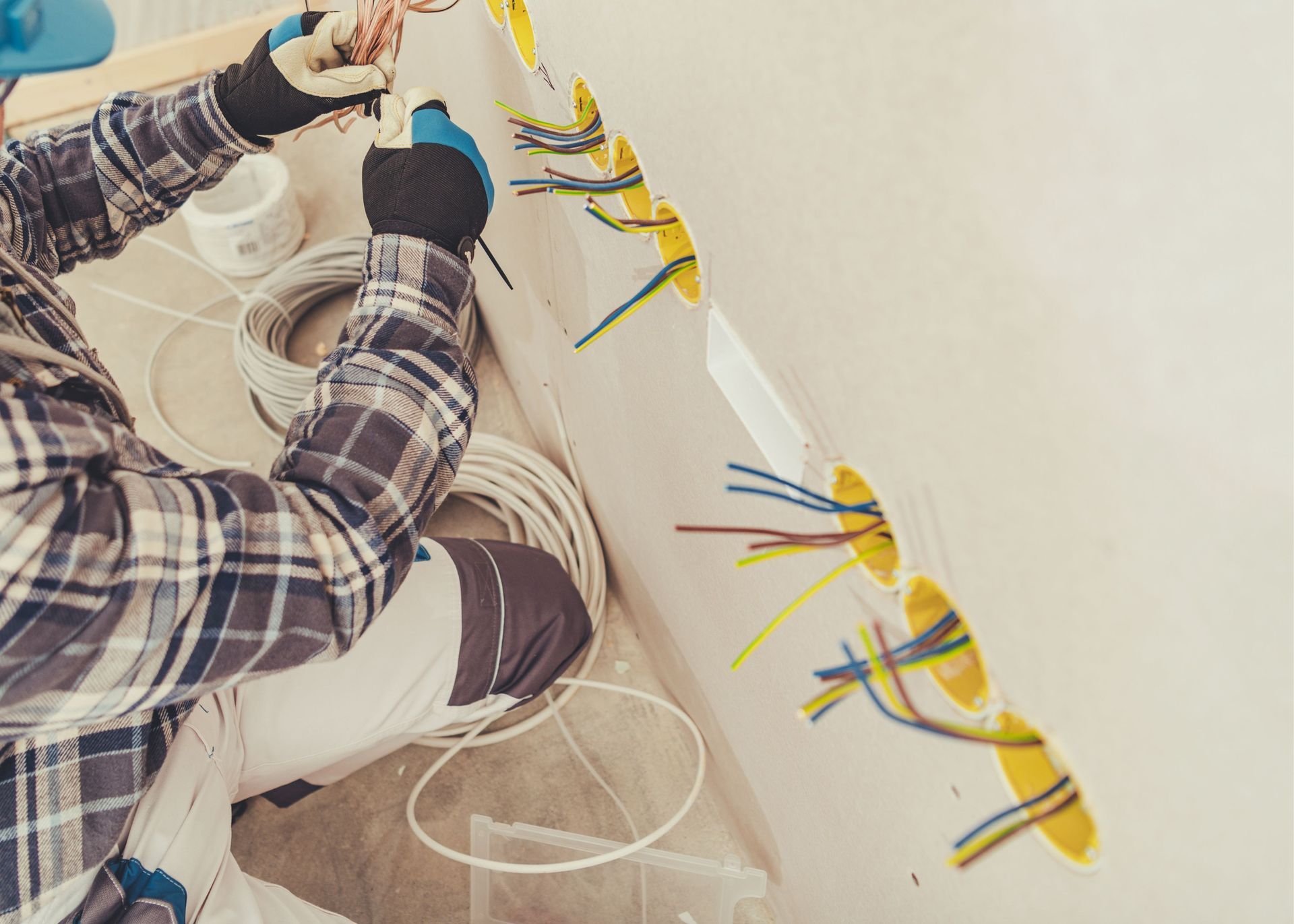 A man is installing electrical wires on a wall.