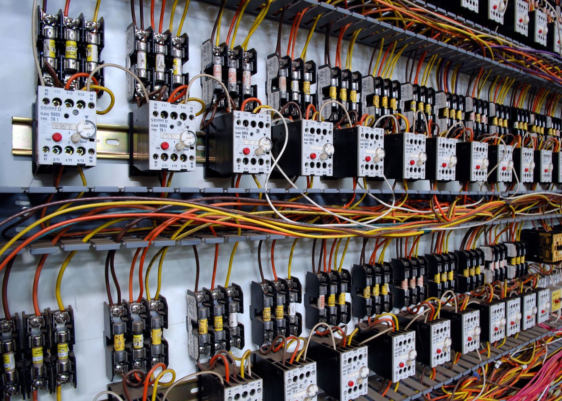 A wall filled with lots of electrical equipment and wires