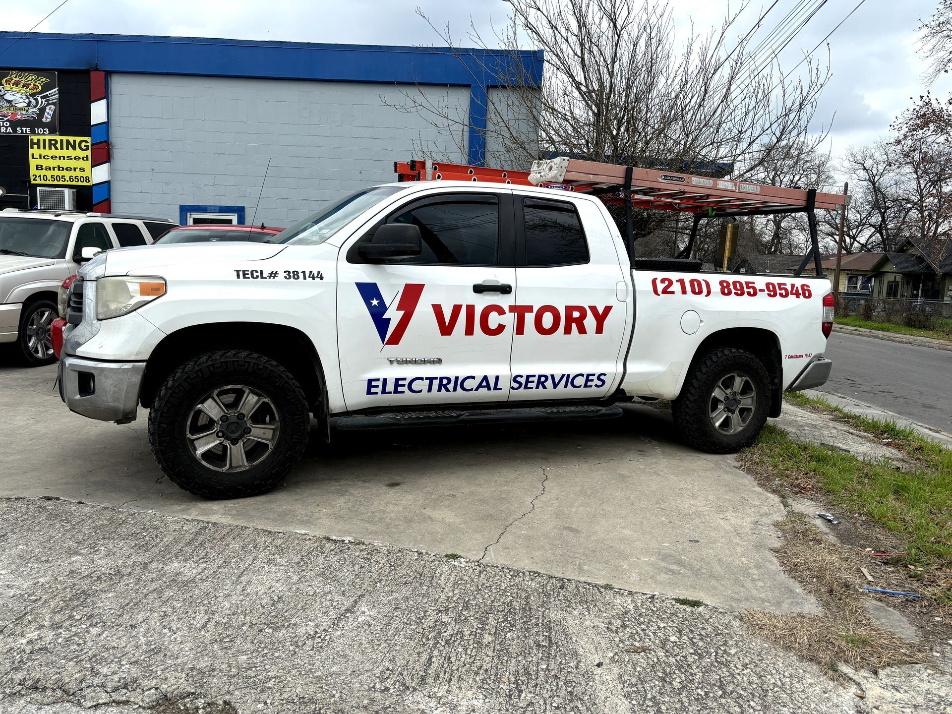 A victory electrical services truck is parked in front of a building.