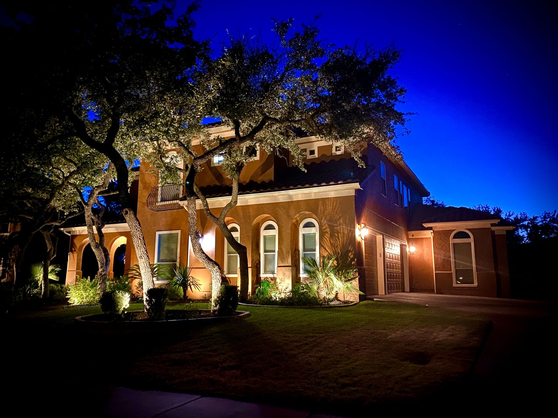 A large house is lit up at night with trees in front of it