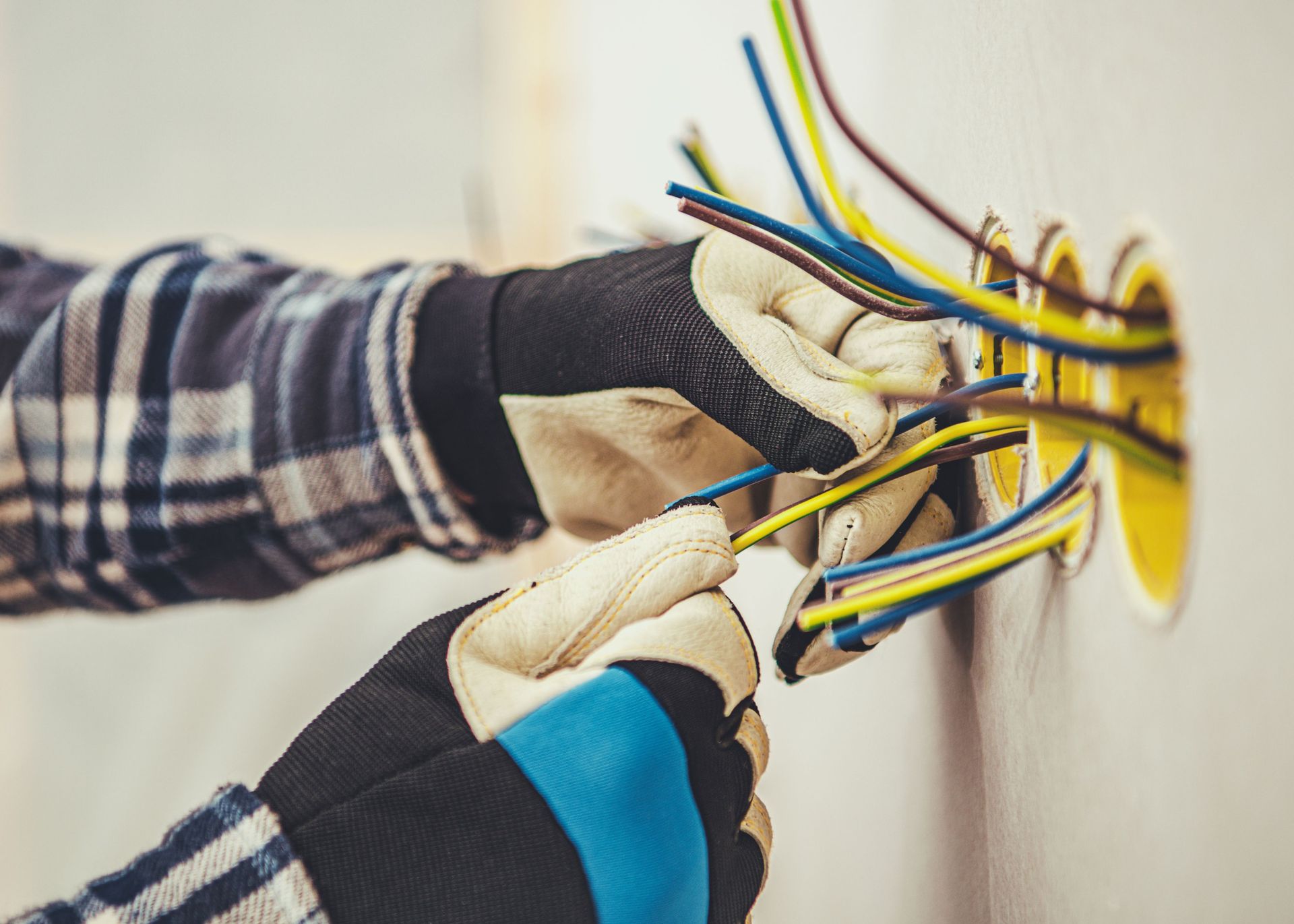 An electrician is plugging wires into a wall outlet.