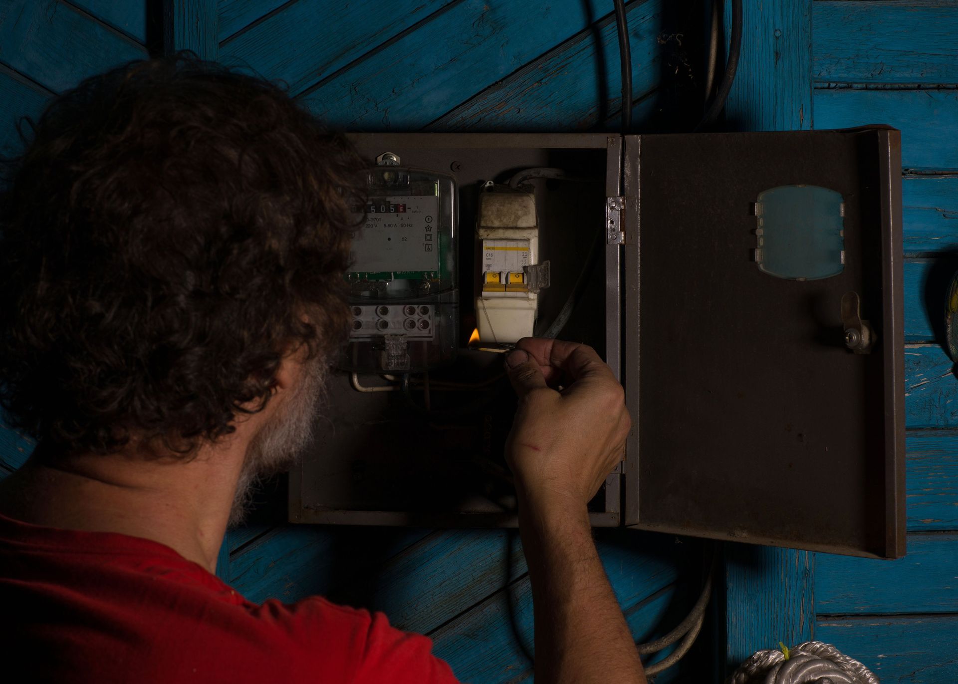 A man is working on an electrical box in the dark.