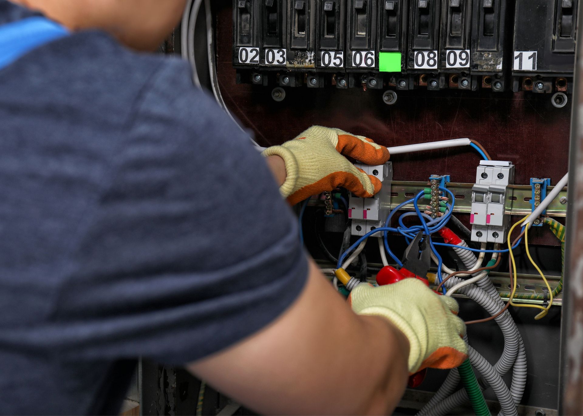A man is working on an electrical box with a screwdriver.