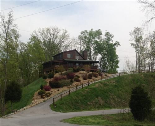 A large house sits on top of a hill surrounded by trees