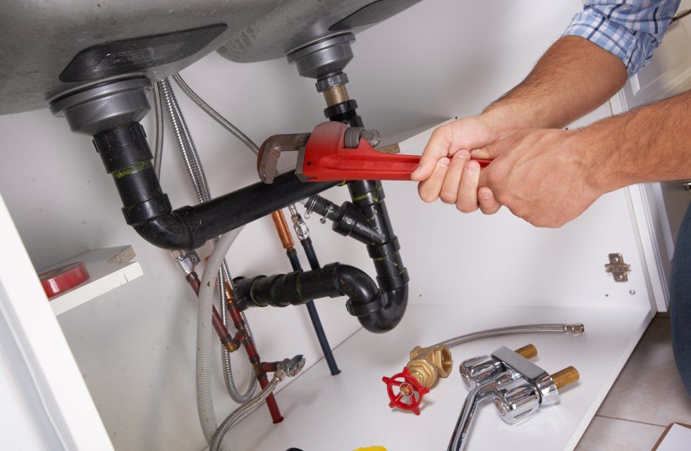 a male plumber fixing sink pipe