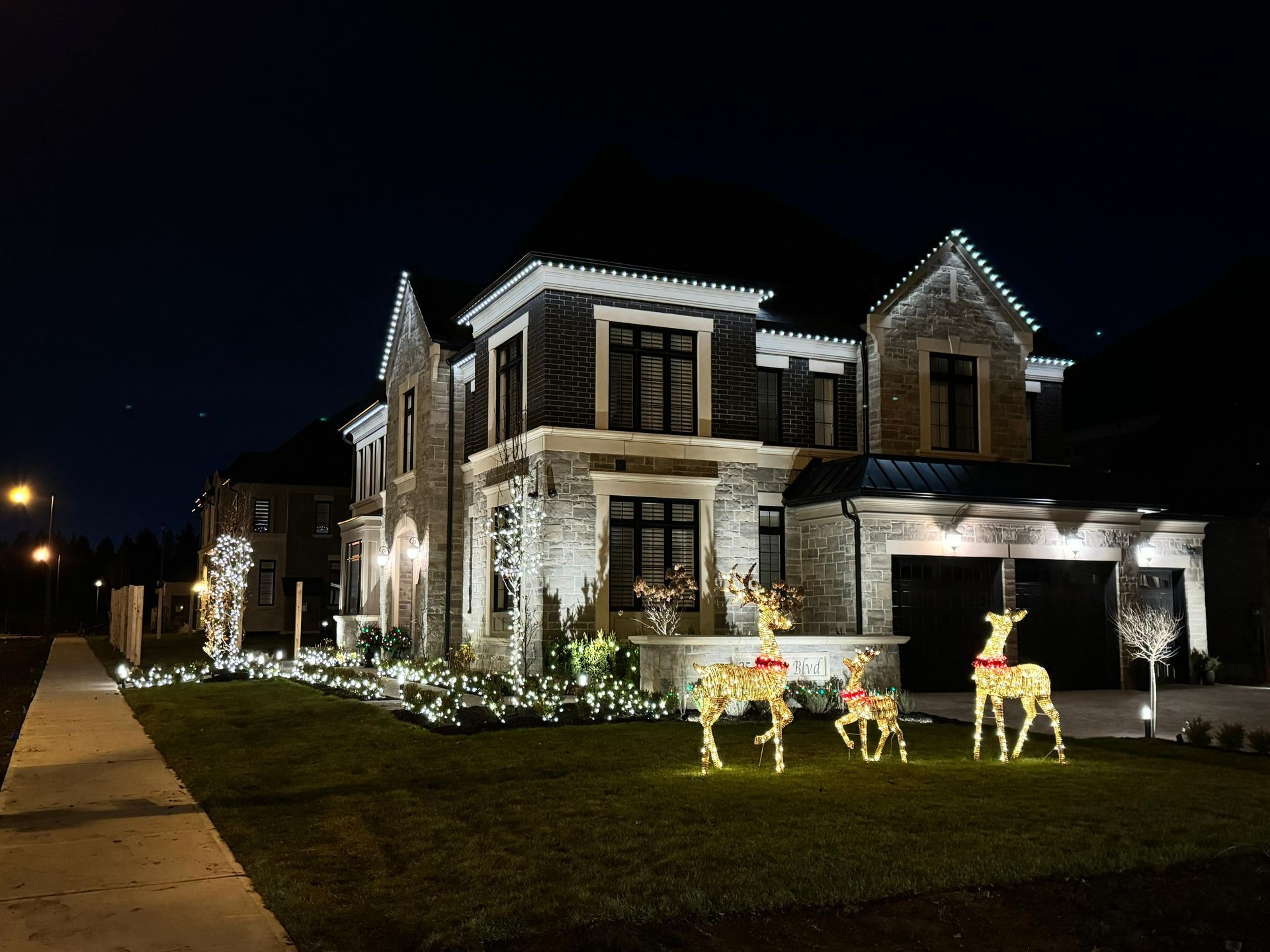Festive permanent holiday lighting on suburban home with LED deer decorations