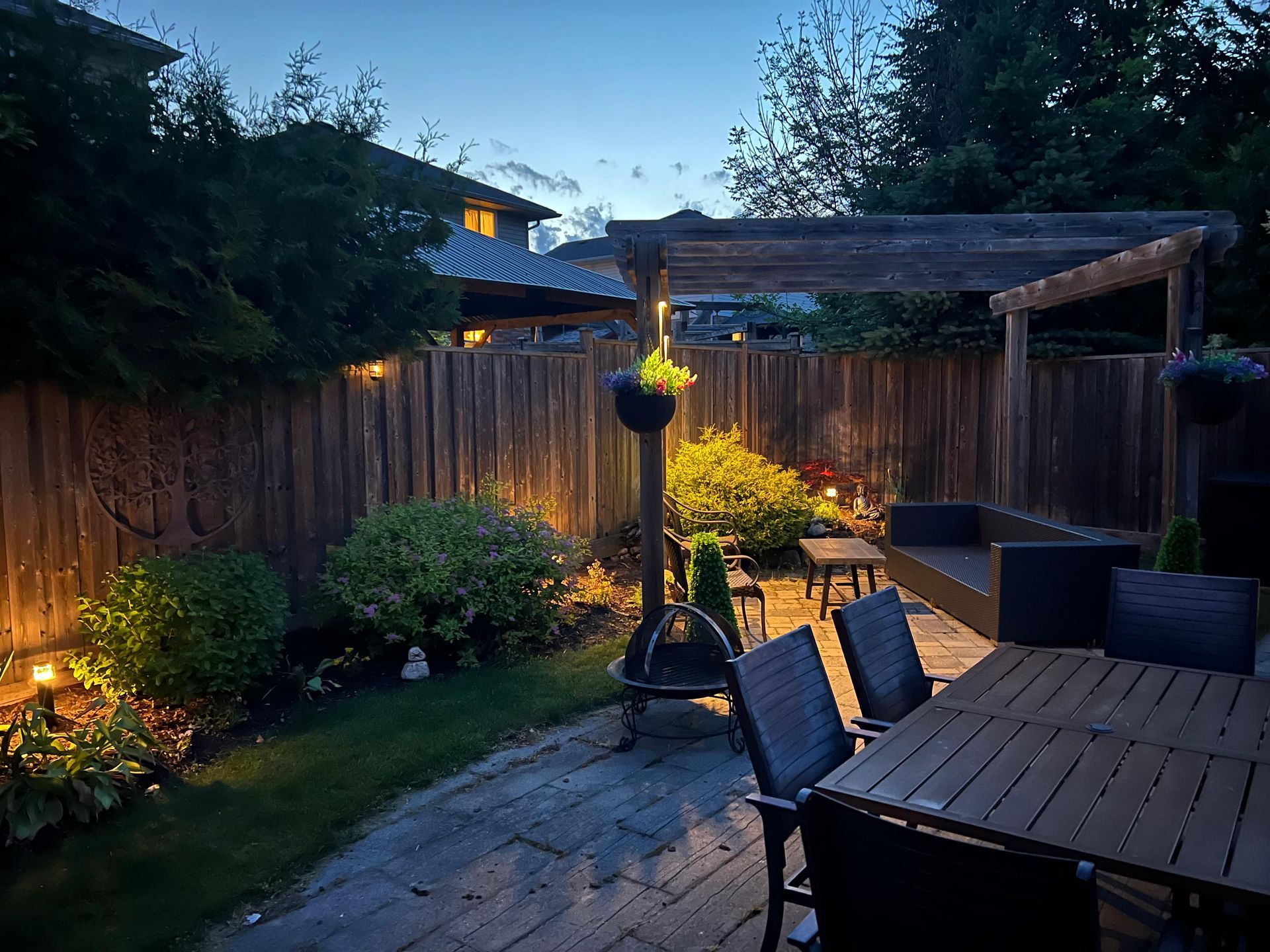 Private garden space with fence and pergola illuminated by landscape lights