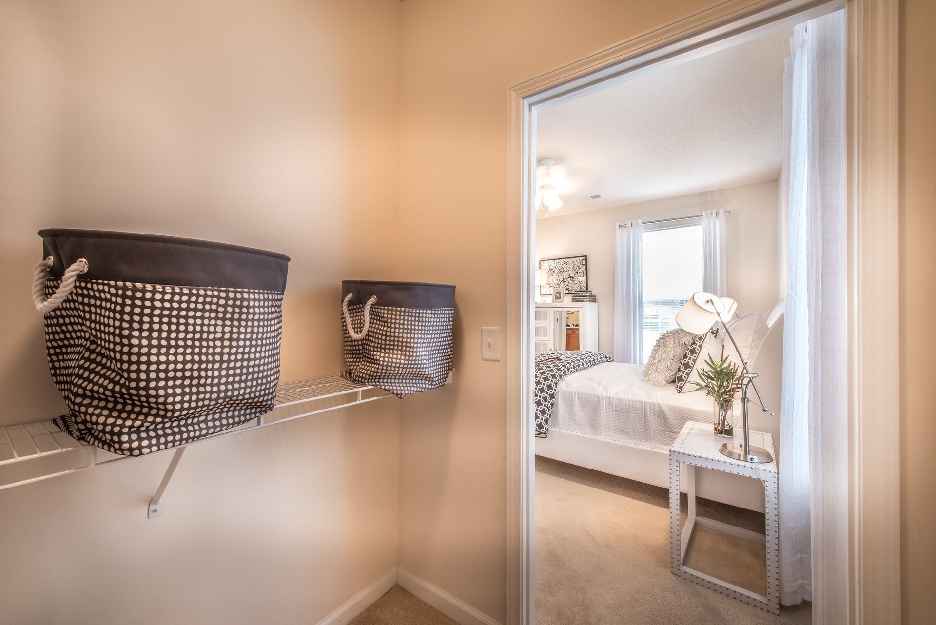 Wall-mounted woven storage baskets beside a doorway, with a softly lit bedroom visible through the opening at Walden at Chatham Center Apartments in Savannah, GA
