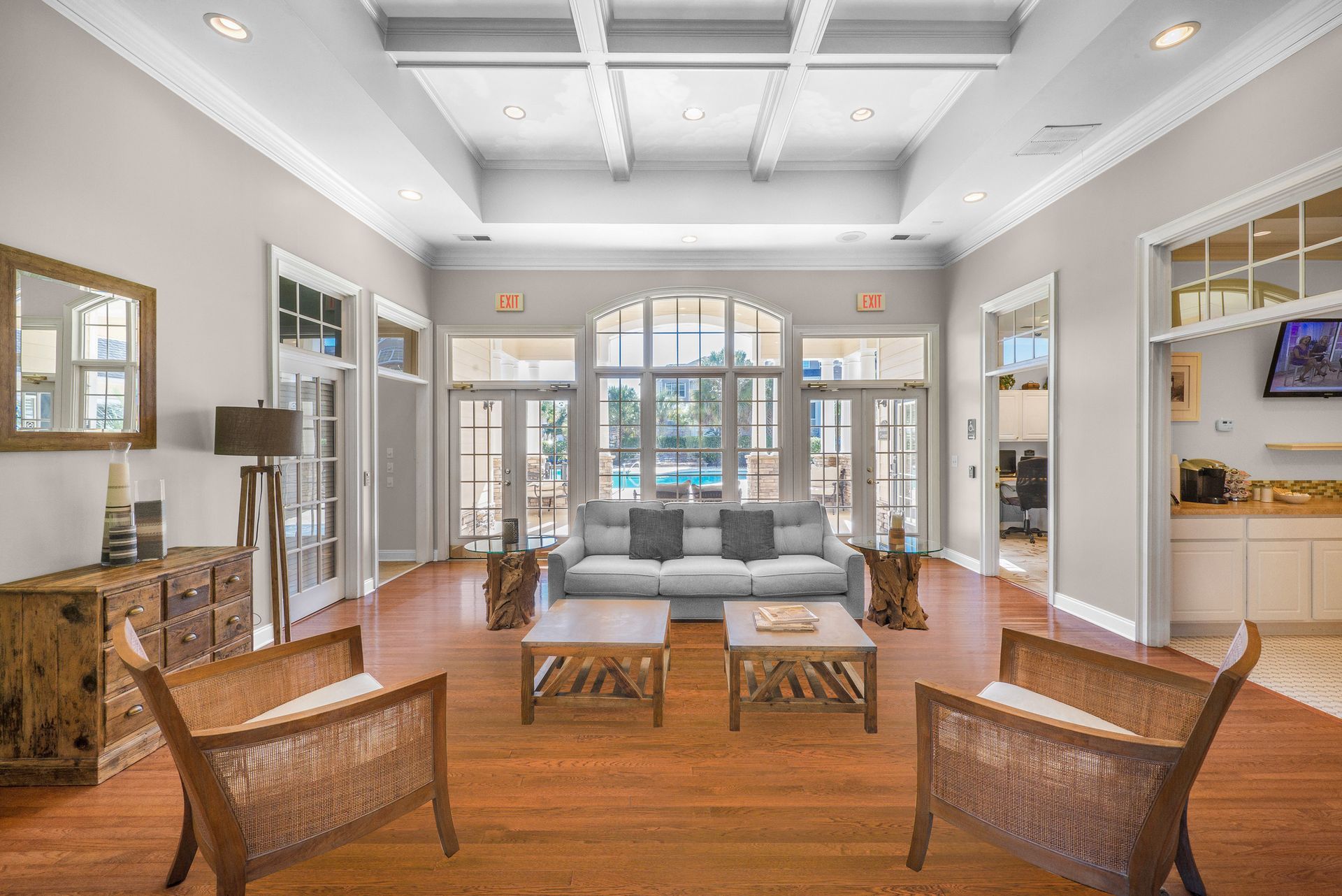 Bright living room with vaulted ceiling, blue sofa, wicker chairs, and French doors opening to a balcony at Walden at Chatham Center Apartments in Savannah, GA.