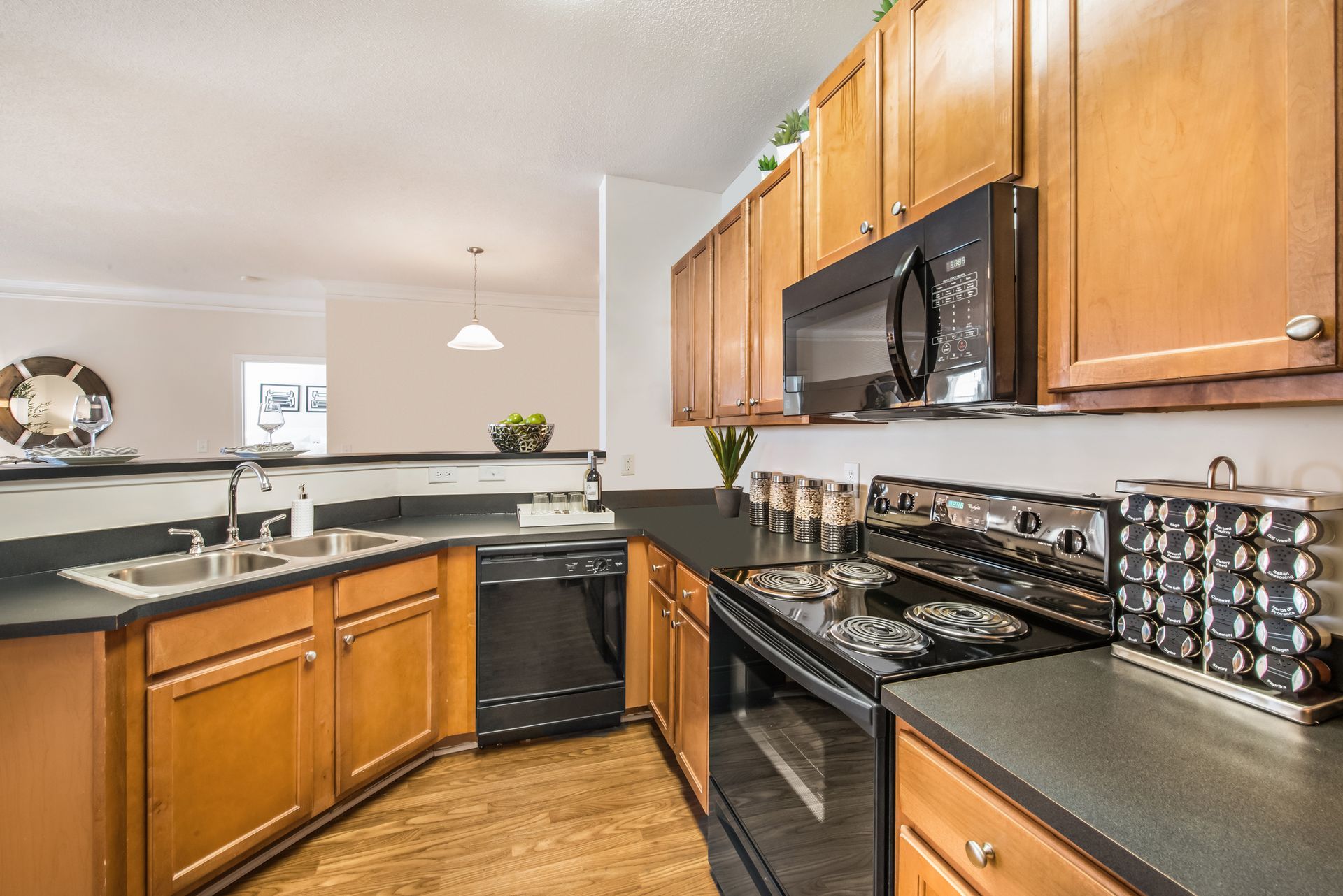 Modern kitchen with black appliances, wood cabinets, and granite countertops at Walden at Chatham Center Apartments in Savannah, GA