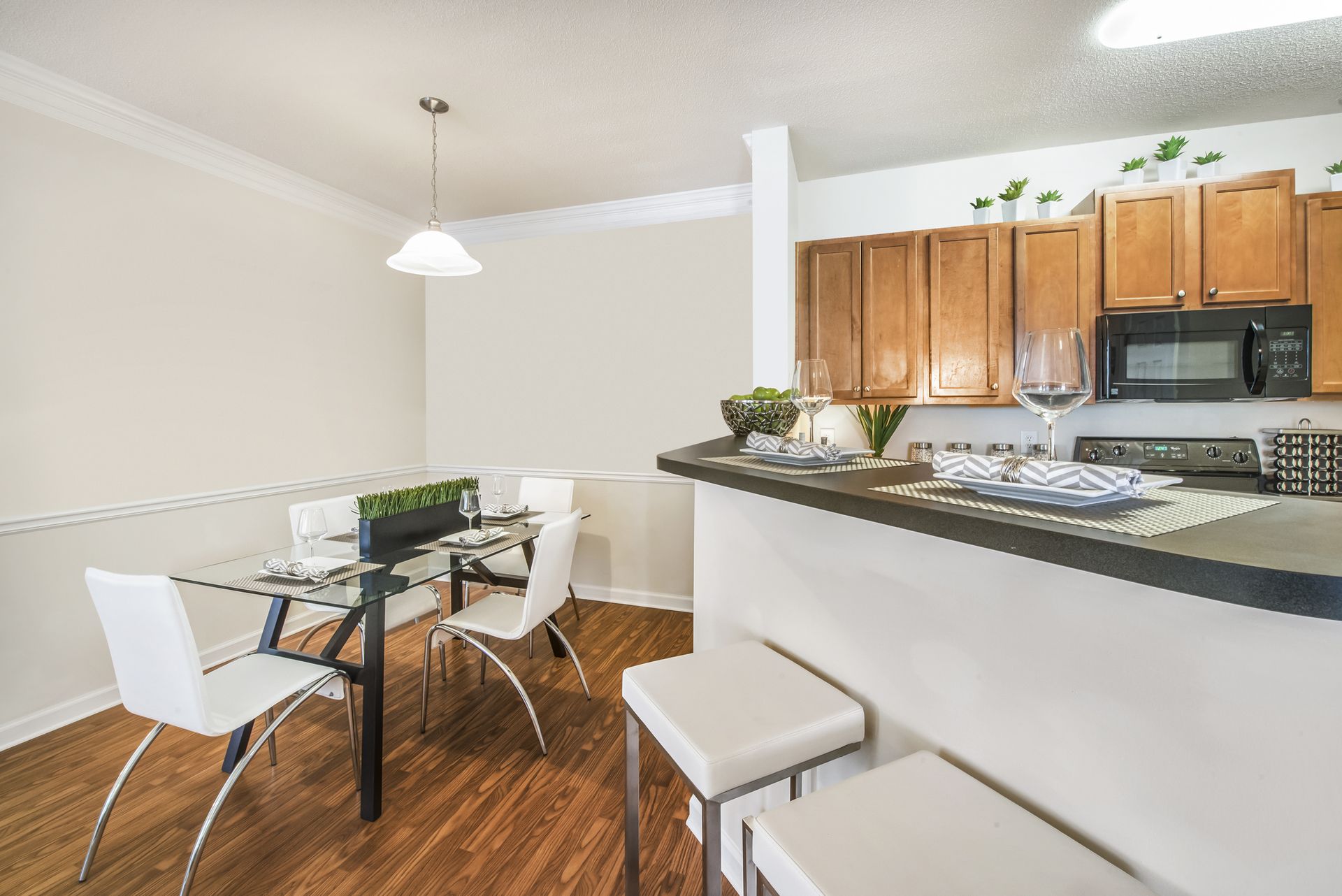 Bright kitchen and dining area with wood cabinets, black countertops, and a glass table with white chairs at Walden at Chatham Center Apartments in Savannah, GA