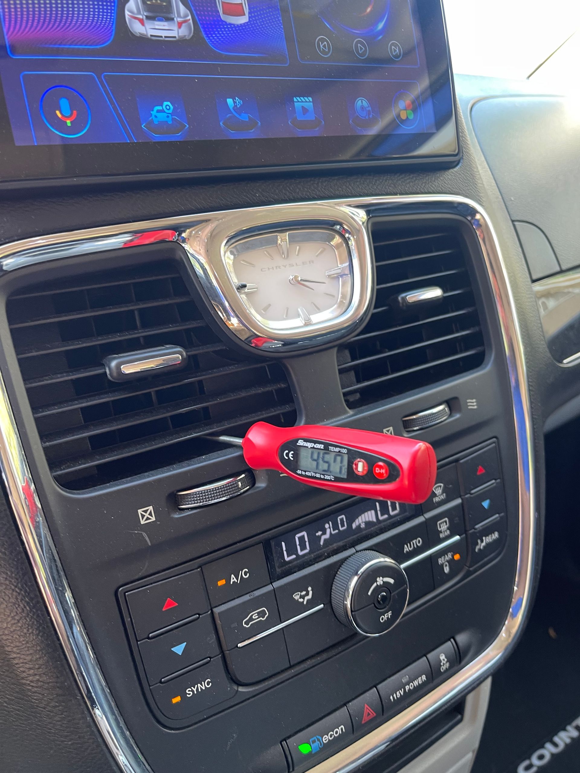 A clock is sitting on the dashboard of a car.