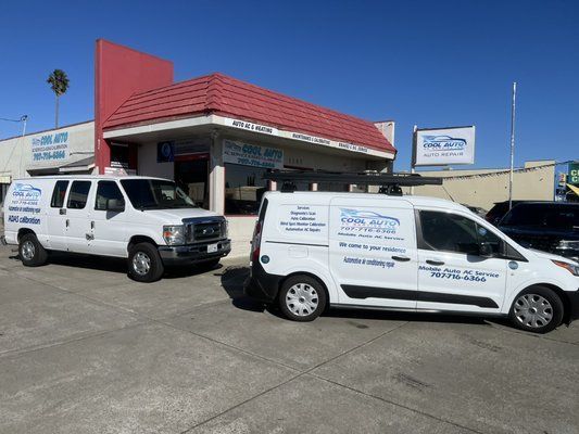 Two white vans are parked in front of a building.