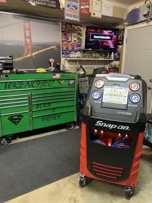 A snap on air conditioner is sitting in a garage next to a green toolbox.