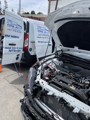 Two white vans are parked next to each other with the hoods open.