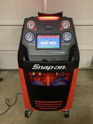 A snap on air conditioning machine is sitting in front of a garage door.