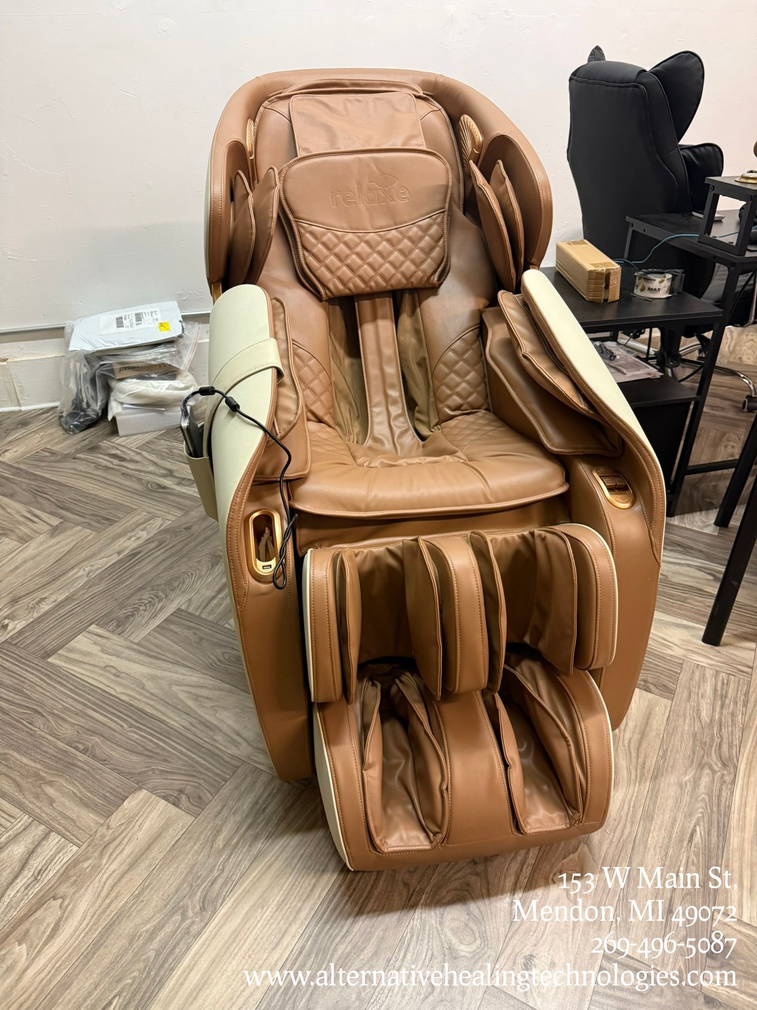 Brown and beige massage chair, reclined, in a room with light wood flooring.