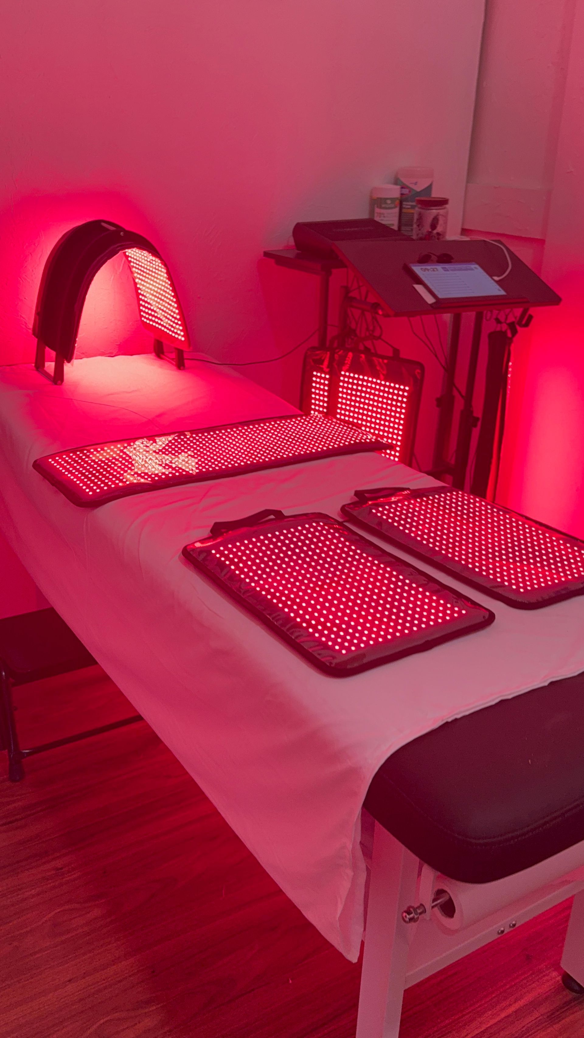 Red light therapy equipment on a massage table in a treatment room.