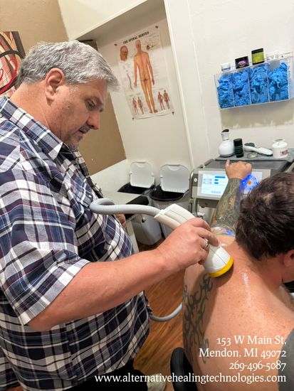 Doctor using a handheld SoftWave Acoustic Sound device on a patient’s neck and rotator cuff in a clinic exam room
