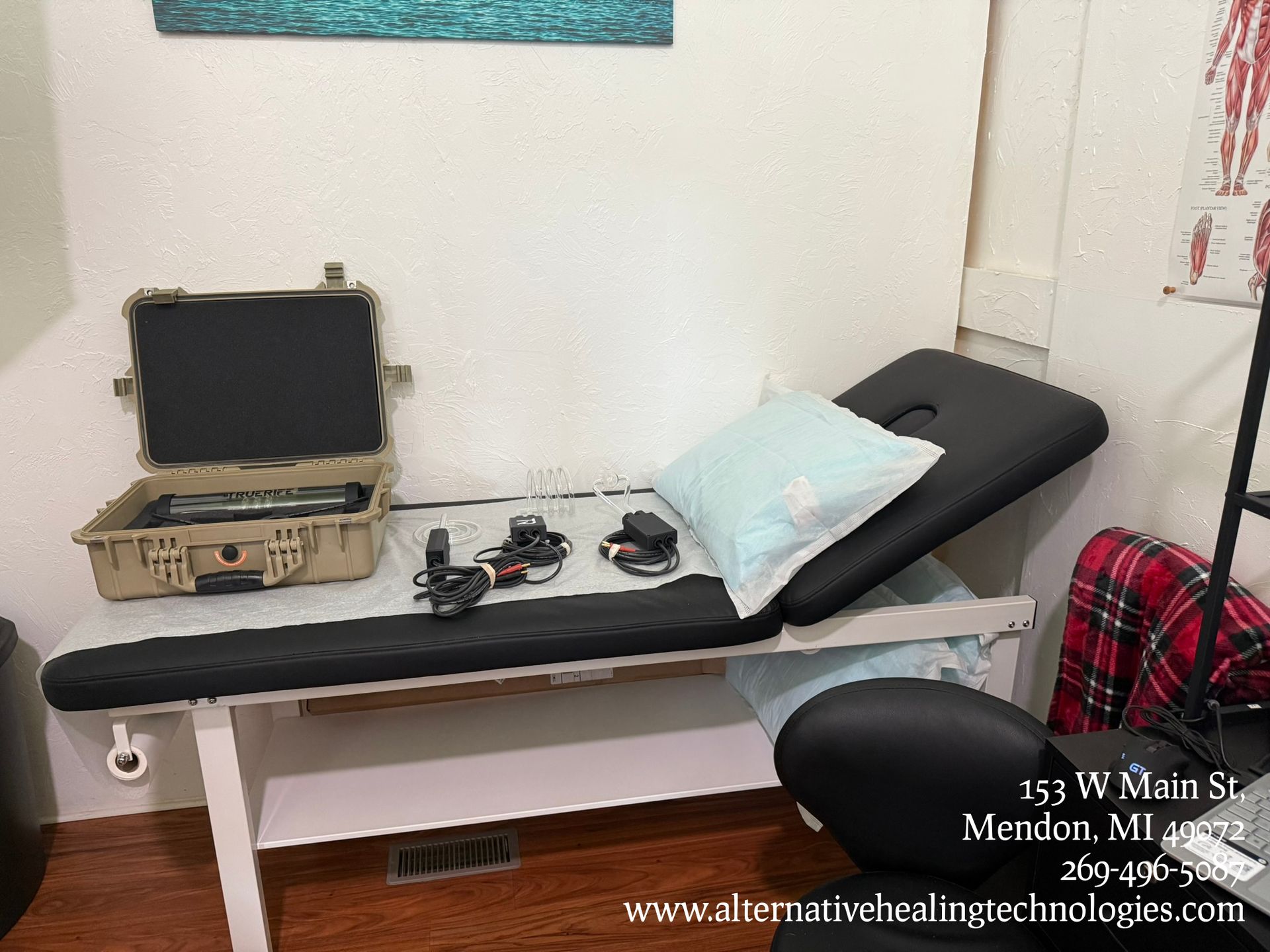 A medical examination table with equipment, a pillow, and a case in a clinic setting.