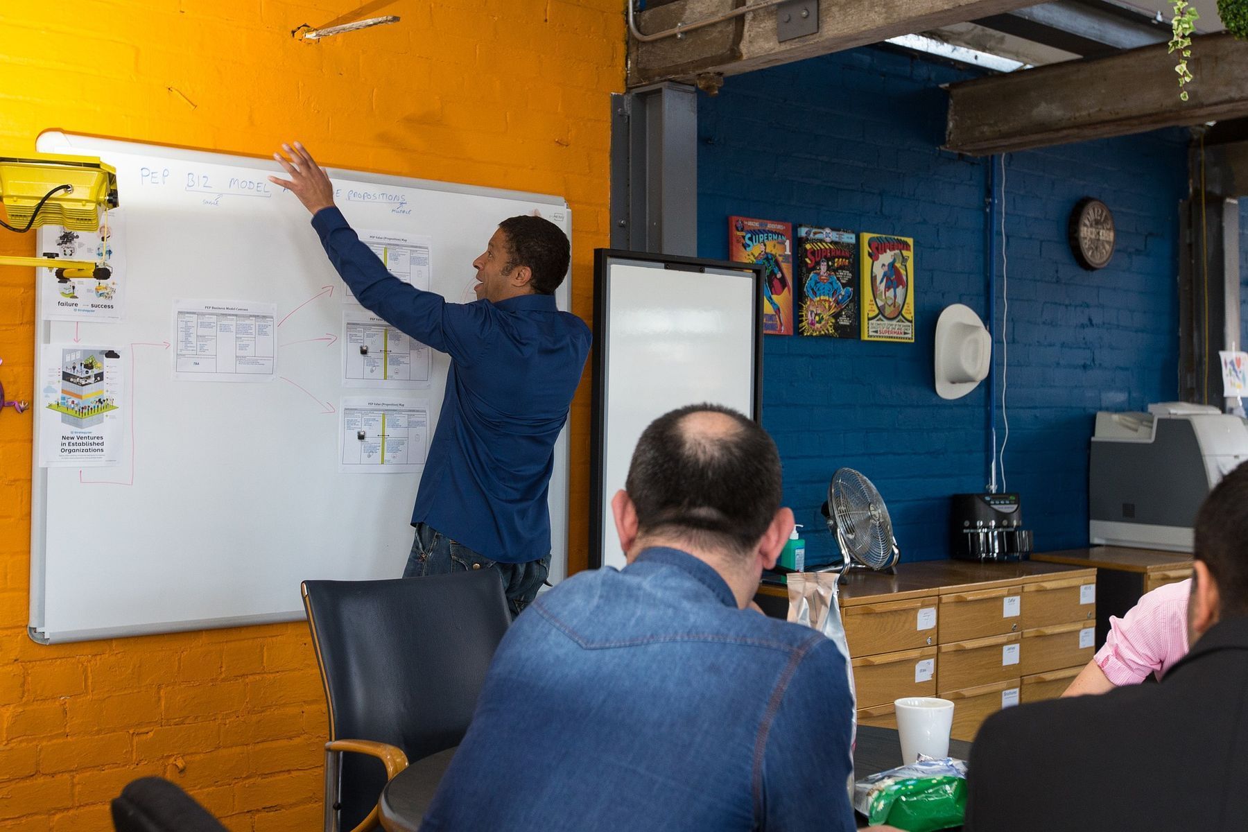 Facilitator mapping a community system on a whiteboard with a group seated around the room