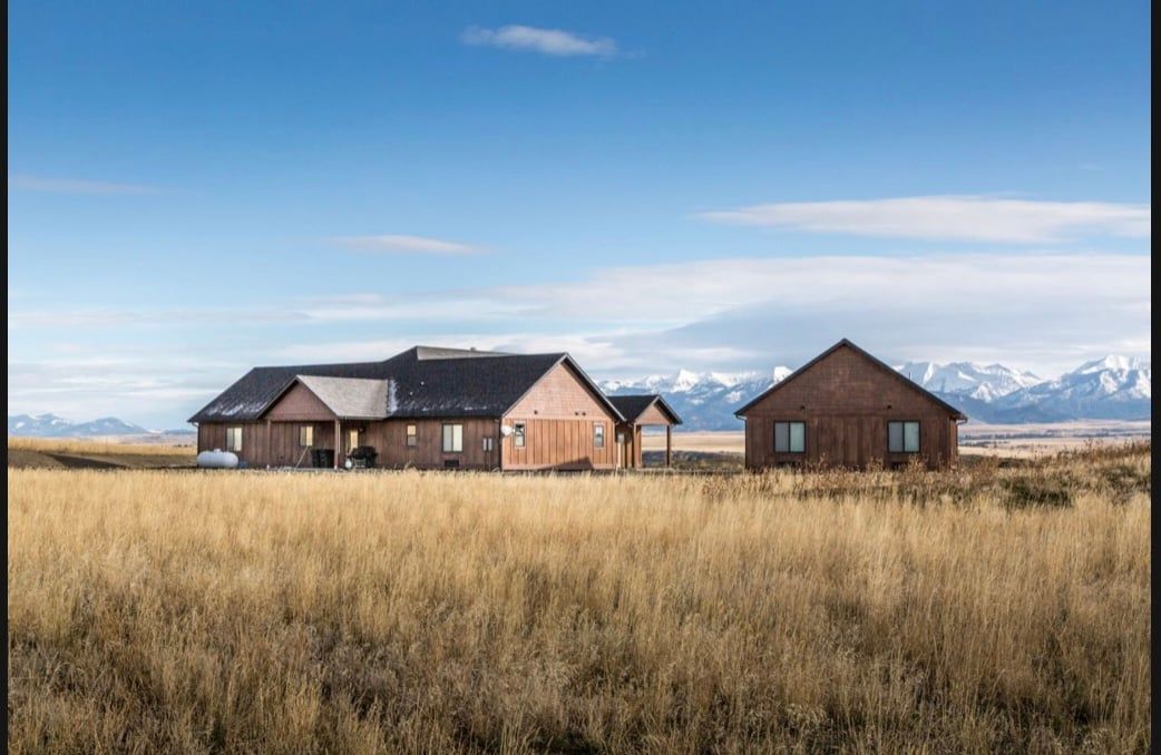 There are two houses in the middle of a field.