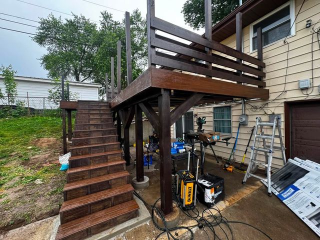 Wooden deck and stairs under construction beside a house, with tools and materials underneath.