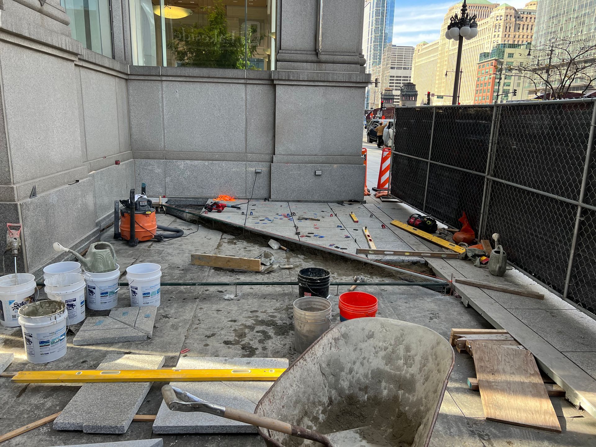 A construction site with a fence and a lot of tools on the ground.