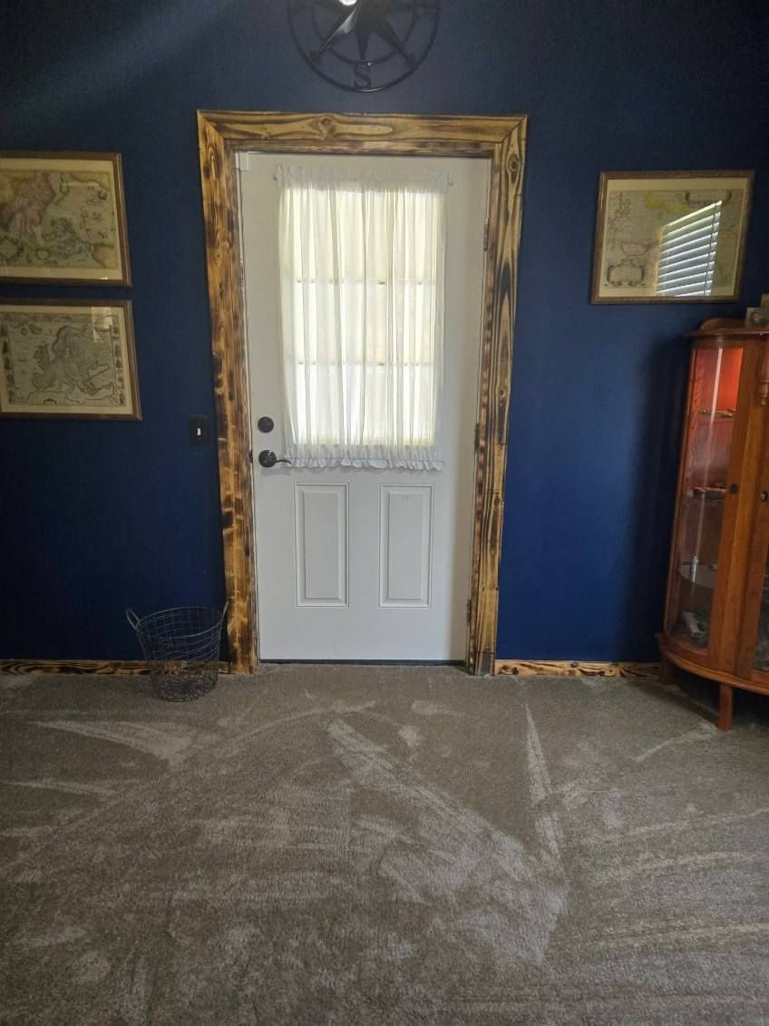 Blue room with a white door, framed wall art, and a wooden cabinet on the right.
