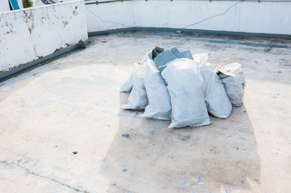 A Pile Of White Construction Bags Sitting On A Flat, Weathered Rooftop — HJK Plastering In Kyogle, NSW