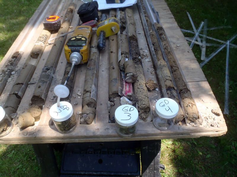 Soil core samples laid out for analysis with instruments; jars of soil samples.