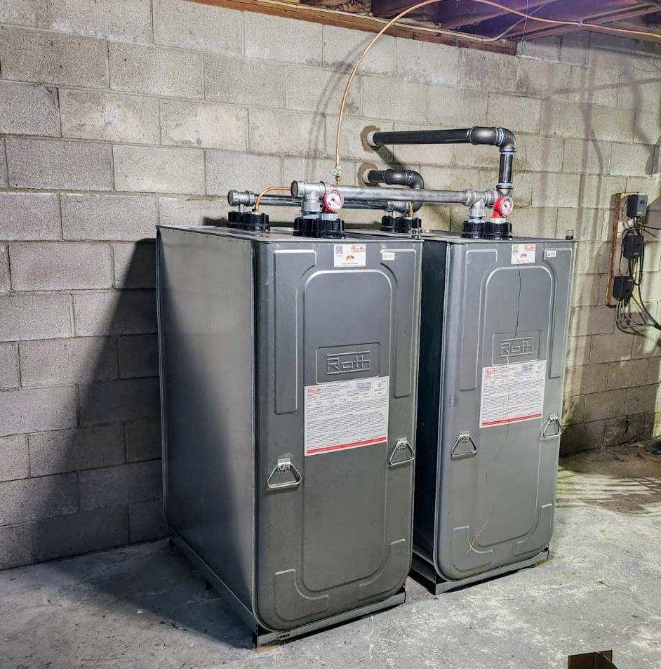 Two large gray rectangular heating units against a cinder block wall. Copper pipes run overhead.
