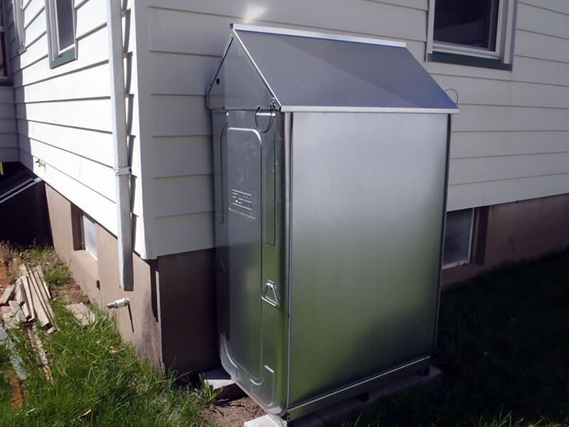 Metal utility box mounted on a house exterior with a sloped roof.