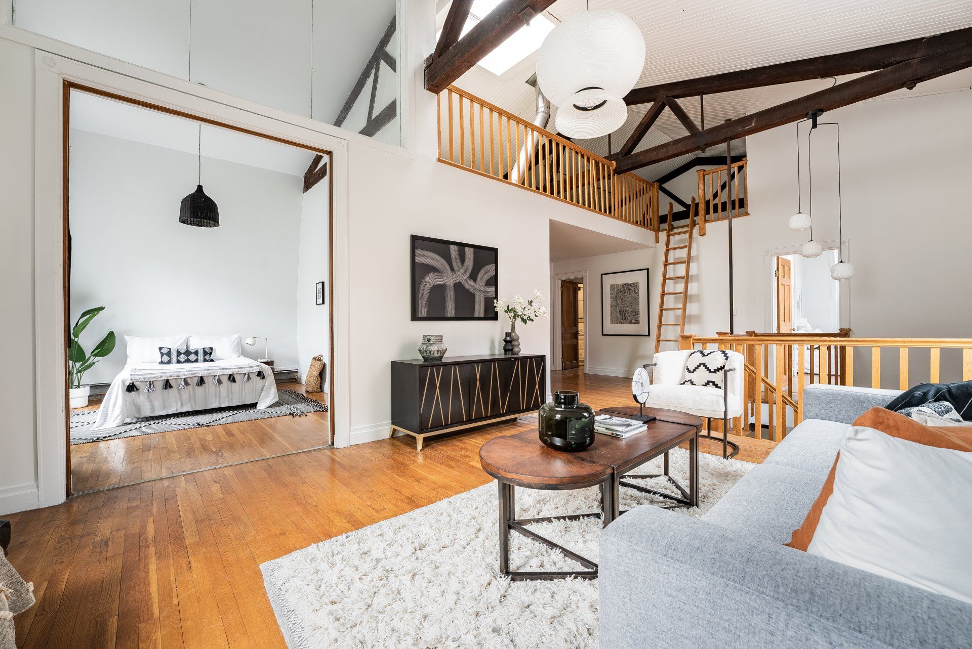 A living room with a couch , coffee table , and stairs leading to the bedroom.