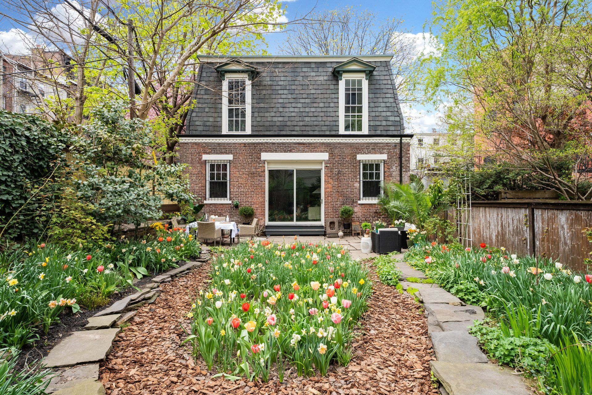 A brick house with a large garden in front of it.