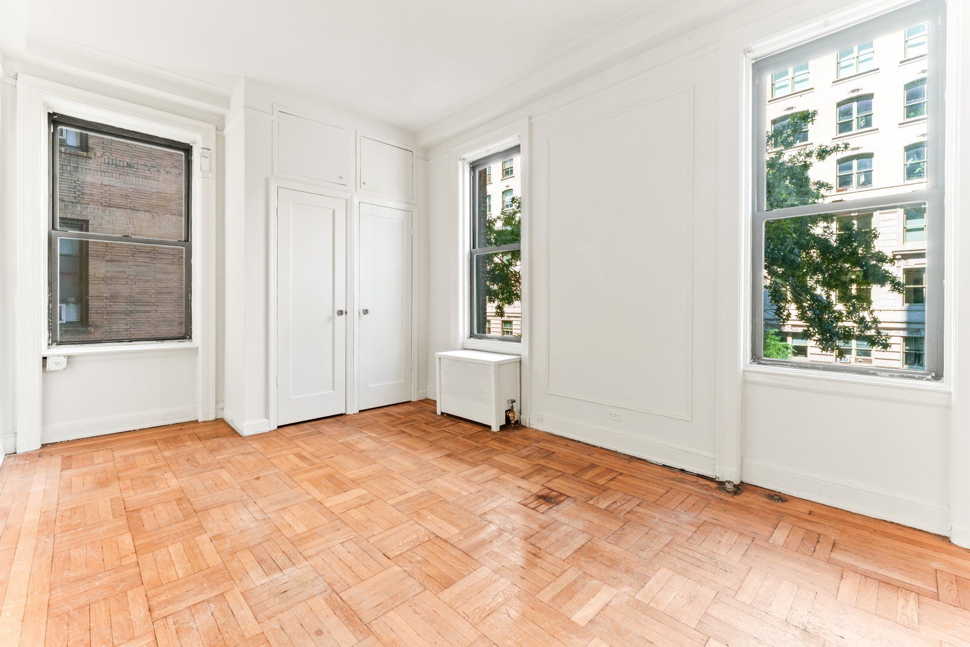 An empty room with a wooden floor and white walls