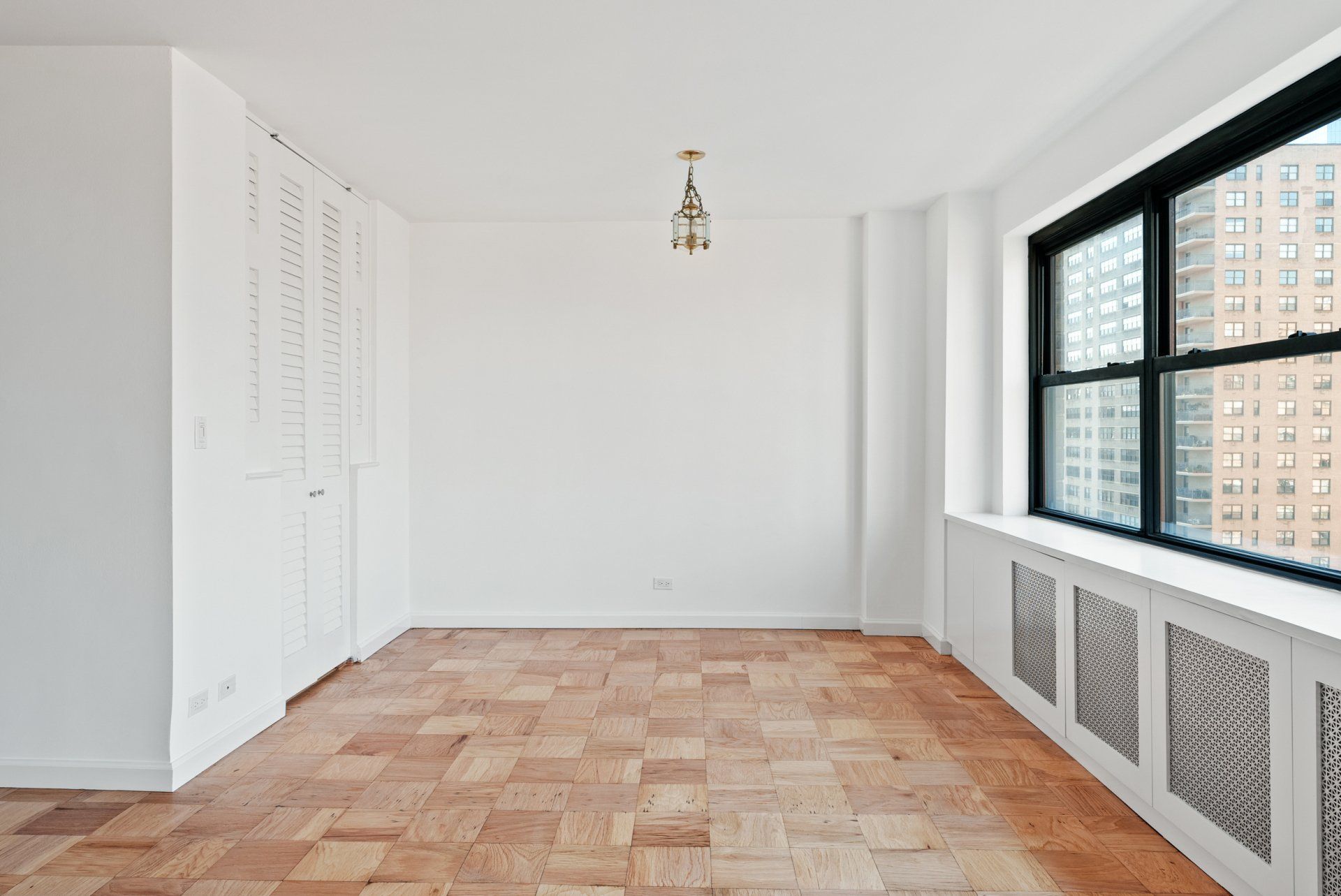 An empty room with hardwood floors and a large window